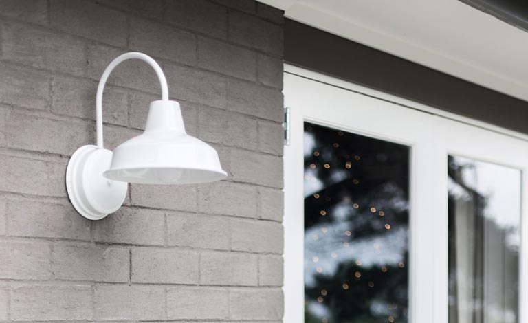 white hampton style light on grey brick with white windows in background