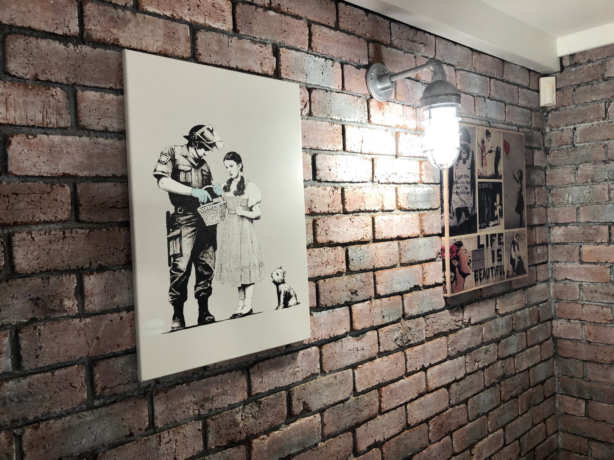 industrial wall light on brickwall with paintings